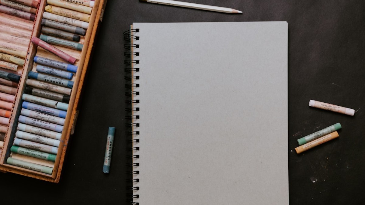 white spiral notebook beside white pen